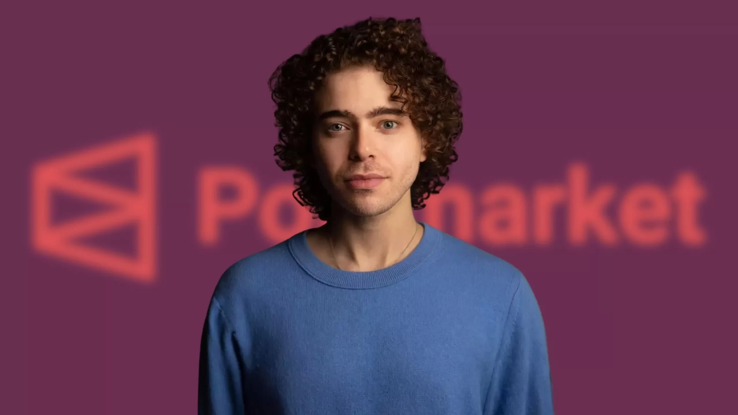 Polymarket founder Shayne Coplan standing in front of the Polymarket logo on a purple background